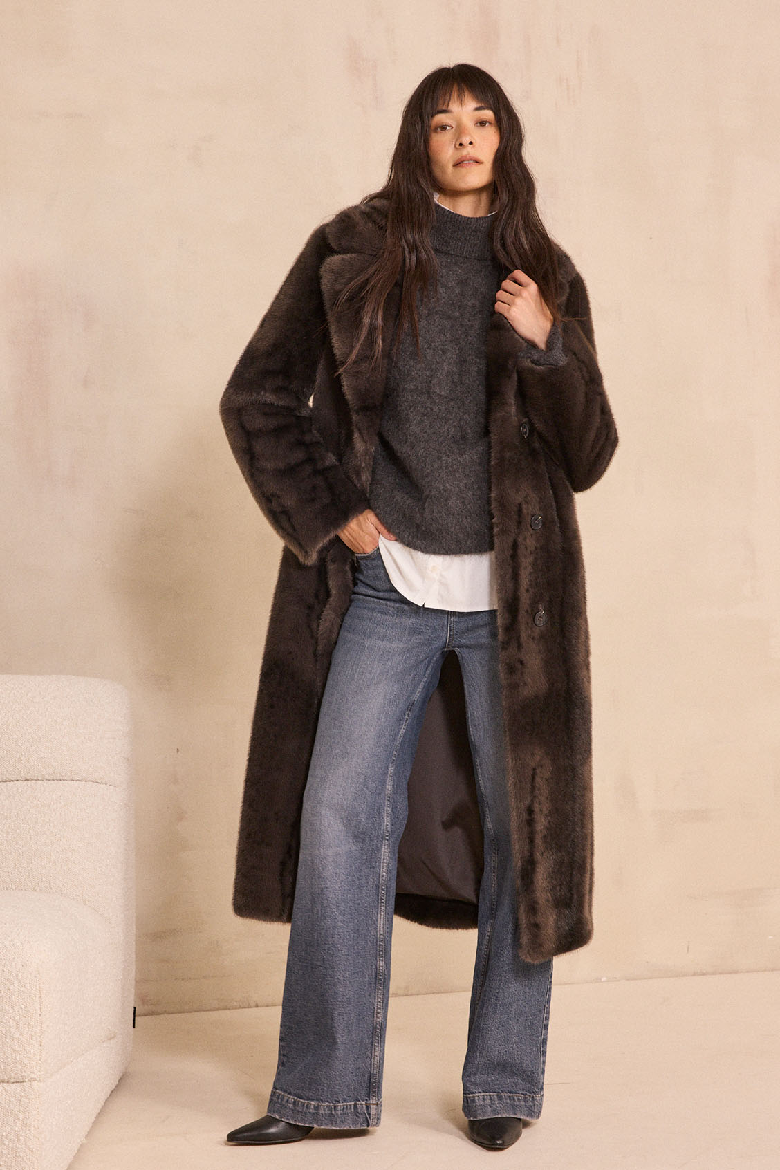 Femme portant un long manteau en fausse fourrure marron foncé et un jean